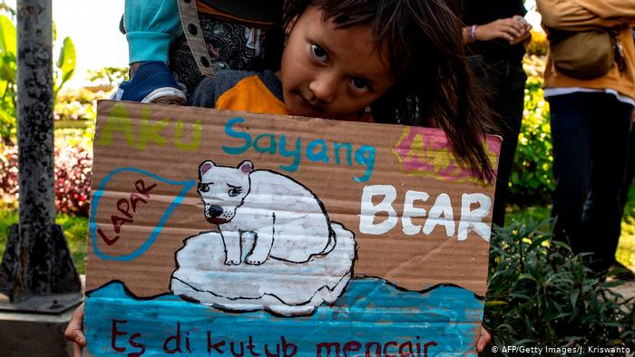 Участница экологической акции с индонезийского острова Ява держит в руках плакат