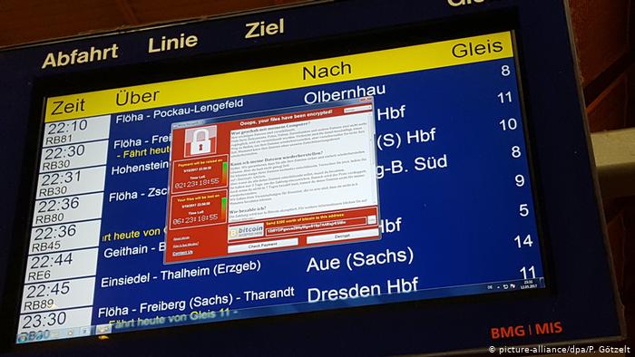 Компьютерное окно с требованием хакеров о выкупе поверх табло с расписанием поездов в Германии