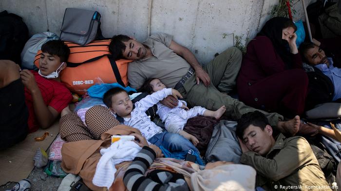 Беженцы лежат на одеялах и сумках на земле под открытым небом