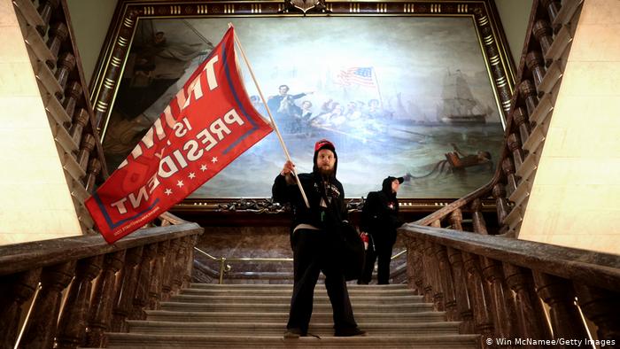 Демонстрант в здании Конгресса с флагом в поддержку Дональда Трампа